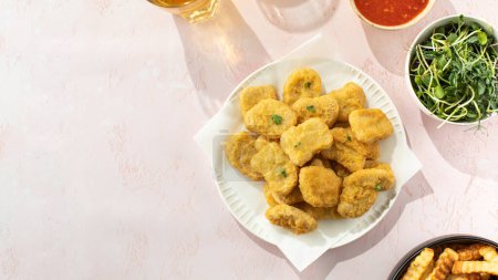 Delicious golden chicken nuggets on a plate on the table. Fast food concept, menu. Copy space