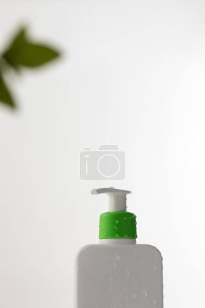 Photo for A minimalist white bottle with a green pump on a soft white background, hinting at natural beauty care. Gel shower, shampoo. - Royalty Free Image