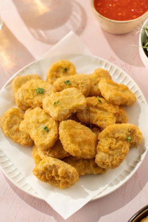 Delicious golden chicken nuggets on a plate on the table. Fast food concept, menu.