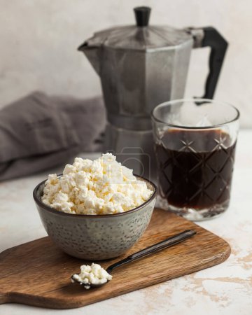 Rustic breakfast scene with crumbly cottage cheese and robust black coffee. Dairy product