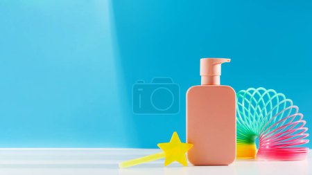 Colorful kids bath scene with pastel soap dispenser, slinky toy, and star wand on blue. Copy space