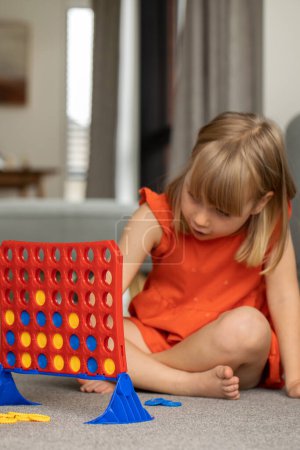 Cute little girl strategizing in Connect Four. Concept of Logic game