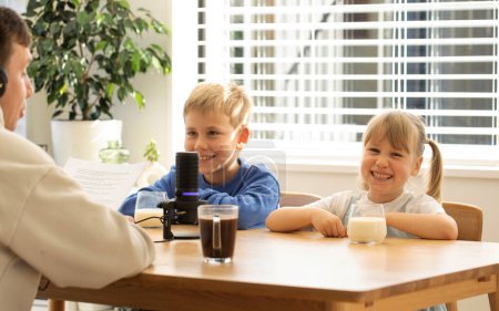 Two children smiling during a family podcast interview, with milk and cookies on the table. The concept of blogging and podcasting.