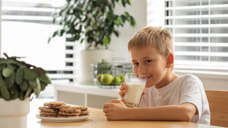 Un niño sonriente con leche fresca de granja y galletas caseras. El concepto de desayuno, productos lácteos