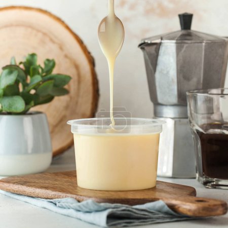 Creamy condensed milk pouring from a spoon, perfect for desserts and sweetening beverages.