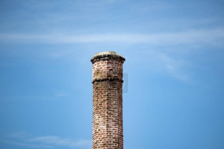 Foto de Antigua chimenea hecha de ladrillos con cielo azul sobre fondo - Imagen libre de derechos