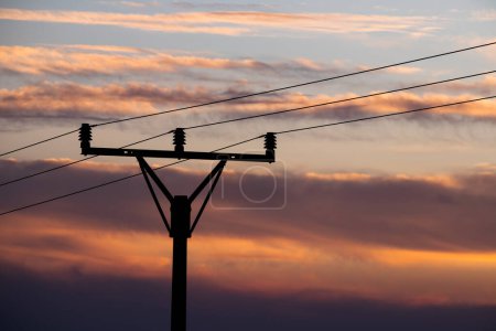 Téléchargez les photos : Silhouette poteau ligne électrique détail avec coucher de soleil ciel sur fond - en image libre de droit