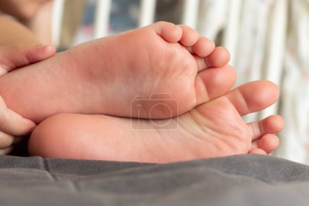 Photo for Baby feet detail with blurred wooden bed on background - Royalty Free Image