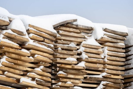 Foto de Pila de tablas de madera cubierta de nieve - construcción de madera de fondo de invierno - Imagen libre de derechos