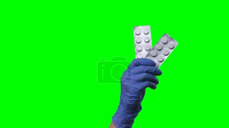 Photo for Woman hand in latex blue glove is showing a blisters of pills. Doctor arm in protective medical glove demonstrating medicines, vitamins, or antibiotics. Concept of treatment of coronovirus, smallpox - Royalty Free Image