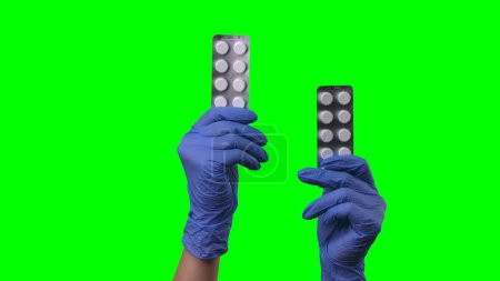 Foto de Las manos de mujer con guantes azules de látex muestran ampollas de pastillas. Brazos médicos en guantes médicos protectores que demuestren medicamentos, vitaminas o antibióticos. Concepto de tratamiento del coronovirus - Imagen libre de derechos