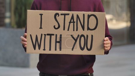 Photo for I STAND WITH YOU on cardboard poster in hands of male protester activist. Stop Racism concept, No Racism. Rallies against racism and police brutality. Peaceful life of blacks matters. City street - Royalty Free Image