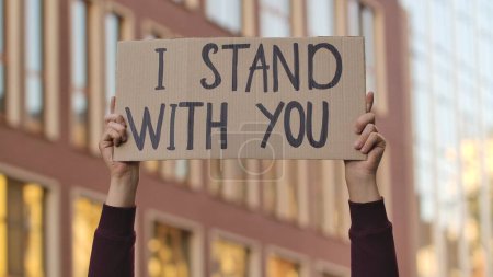 Photo for I STAND WITH YOU on cardboard poster in hands of male protester activist. Stop Racism concept, No Racism. Rallies against racism and police brutality. Peaceful life of blacks matters. City street - Royalty Free Image