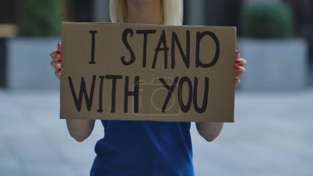 Photo for I STAND WITH YOU on cardboard poster in hands of female protester activist. Stop Racism concept, No Racism. Rallies against racism and police brutality. Peaceful life of blacks matters. City street - Royalty Free Image