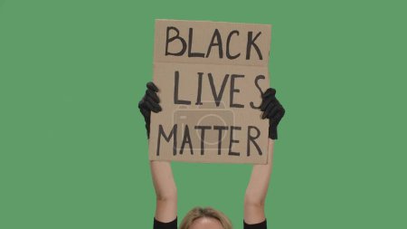 Foto de Las manos de una persona desconocida con guantes negros levantan el cartel de cartón. Stop Racism concept, No Racism. Reuniones contra el racismo y la brutalidad policial. La vida pacífica de los negros importa - Imagen libre de derechos