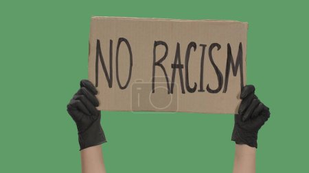 Photo for Hands of an unknown person in black gloves raise cardboard poster NO RACISM. Stop Racism concept, No Racism. Rallies against racism and police brutality. Peaceful life of blacks matters. Isolated - Royalty Free Image