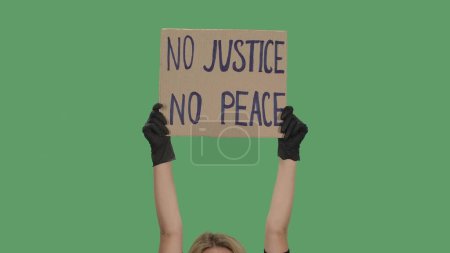 Photo for Hands of an unknown person in black gloves raise cardboard poster NO JUSTICE NO PEACE. Stop Racism concept, No Racism. Rallies against racism and police brutality. Peaceful life of blacks matters - Royalty Free Image