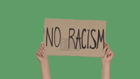 Photo for NO RACISM. Protest text message on cardboard. Stop racism. Police violence. Banner design concept. Hands of women raising up poster on green screen, chroma key. Rallies against racism and police - Royalty Free Image