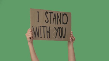 Photo for Hands of women raising up cardboard poster I STAND WITH YOU. Stop Racism concept, No Racism. Rallies against racism and discrimination. Peaceful life of blacks matters. Isolated green screen chroma - Royalty Free Image