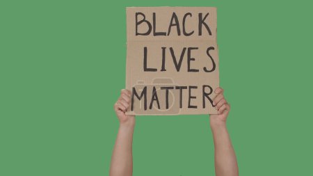 Photo for BLACK LIVES MATTER. Protest text message on sign cardboard. Stop racism. Police violence. Banner design concept. Hands of men raising up poster on green screen, chroma key. Rallies against racism and - Royalty Free Image