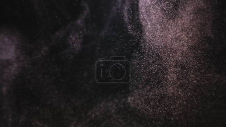 Foto de Nube de partículas de polvo flotantes que brillan en los rayos de luz del estudio sobre un fondo negro. Polvo girando y brillando iluminado por la luz. Macro shot de textura blanca nieve, humo, vapor, niebla - Imagen libre de derechos
