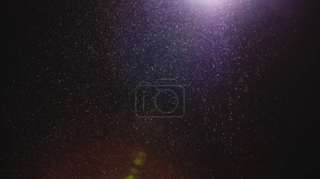 Photo for Natural dust particles floating on black background with light. Glittering sparkling particles in the air with effect bokeh. Macro shot of texture whites snow, smoke, steam, fog with purple glare - Royalty Free Image