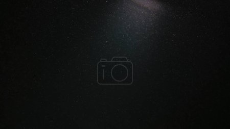 Foto de Una nube mágica de polvo flotando en el espacio sobre un fondo negro. Las partículas brillan y brillan en la luz del estudio. Macro shot de textura blanca nieve, humo, vapor, niebla con luminosidad deslumbrante - Imagen libre de derechos