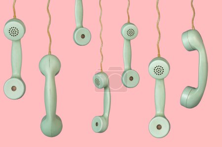 Photo for Many old telephone handsets from rotary landlines hanging from cords on pink background. Plastic grey removed receiver from retro phone with cable. Concept of communication, conversation, connection - Royalty Free Image