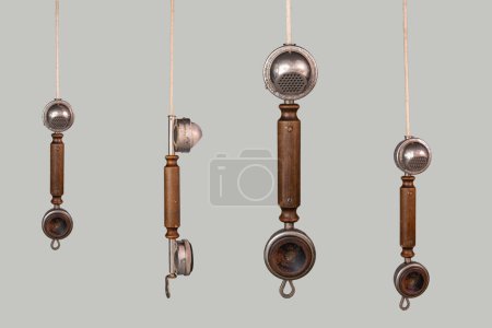 Photo for Set of antique wooden handsets with metal microphone and speaker. Aged telephone receivers hanging from cords on a gray background. Communication, telecommunication, conversation apparatus. Photo in - Royalty Free Image