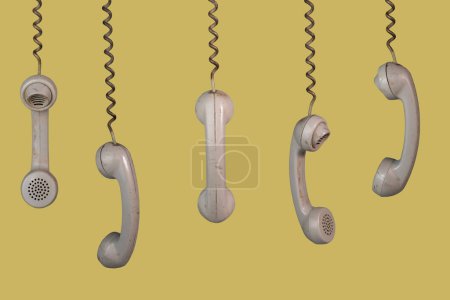 Photo for Many old telephone handsets from rotary landlines hanging from cords on yellow background. Plastic grey removed receiver from retro phone with cable. Concept of communication, conversation, connection - Royalty Free Image