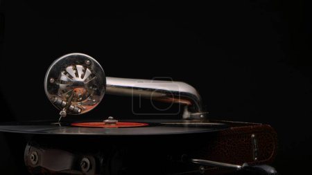 Photo for Vintage old record player gramophone needle on vinyl record. Round shiny metal needle holder head reproducing music. Retro vintage vinyl player on black studio background. Needle old gramophone close - Royalty Free Image