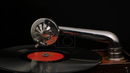 Photo for Vintage old record player gramophone needle on vinyl record. Round shiny metal needle holder head reproducing music. Retro vintage vinyl player on black studio background. Needle old gramophone close - Royalty Free Image