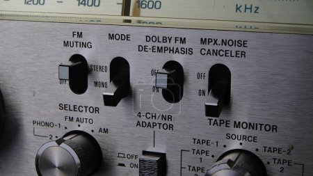 Photo for Control panel with toggle switches, knobs and buttons on a retro turntable in silver. Old analog stereo cassette player with radio. Close up of dashboard with switches and an FM frequency search scale - Royalty Free Image