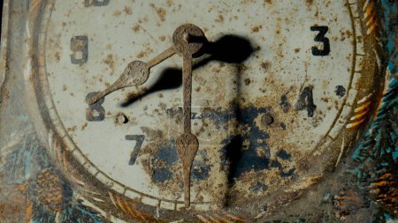 Foto de Old clock dial with rusty minute and hour hands covered corrosion. White face of vintage watch with weathered pattern, scuffs and scratches. Broken retro clock. Part of an antique clock close up. - Imagen libre de derechos