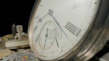 Foto de Dial de reloj de bolsillo vintage gris en la pila de piezas de relojería. Reloj redondo viejo entre engranajes metálicos y mecanismo interno de reloj de bolsillo. Detalles desmontados y reloj de bolsillo vintage en estudio negro - Imagen libre de derechos