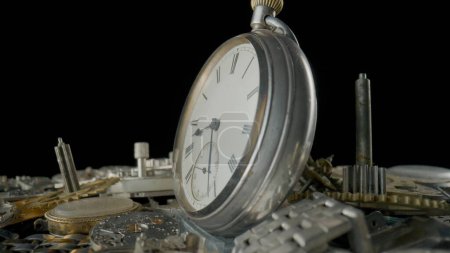 Photo for Side view of old silver pocketwatch on a pile of gears, gearwheels, cogwheels and a metal watch bracelet on black background. Disassembled parts clockwork in workshop, repair. Broken clock mechanism - Royalty Free Image