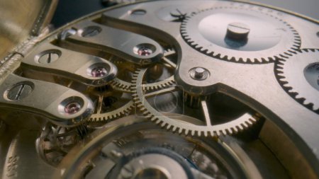 Photo for Internal working mechanism of an antique pocket watch. Reverse side of a pocket watch with an open clockwork. Screws, spring, gears and cogwheels of an old clock. Disassembled pocketwatch. Macro shot - Royalty Free Image