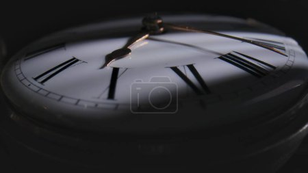Téléchargez les photos : Antique pocket watch with a dark shadow on the white dial. An old round pocket watch with the minute and hour hands stopped. Retro watch with white dial and black Roman numerals. Close up - en image libre de droit