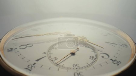 Téléchargez les photos : Antique pocket watch with a white dial and gold hands in bright light. The face of an old clock with numbers extra close up. Round mechanical vintage pocket watch - en image libre de droit
