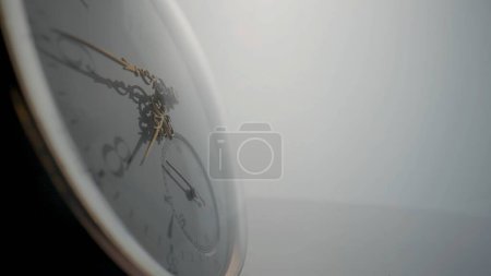 Téléchargez les photos : Side view of antique pocket watch with a white dial and gold hands in bright light. The face of an old clock with numbers extra close up. Round mechanical vintage pocket watch - en image libre de droit