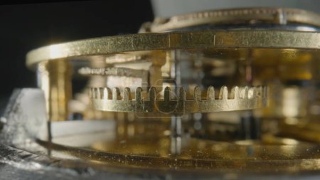 Foto de Vista interior de un reloj de reloj mecánico dorado sobre fondo de estudio aislado negro. Engranajes dorados, engranajes, rueda con dientes. Reloj desmontado con rueda dentada y muelle. Macro tiro de torneado - Imagen libre de derechos