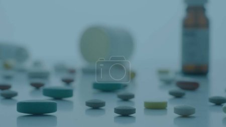Photo for Round and oval pills scattered on table on blue background. Tablets and various medical bottles on table. Close up of vitamins, antibiotics or painkillers. Concept of medicine, health, treatment - Royalty Free Image