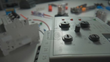 Photo for Phase control relay and relay with electromagnetic coils of direct and alternating current on the table. Close up of equipment with white metal casing, switch buttons and rotary knobs, screwdrivers - Royalty Free Image