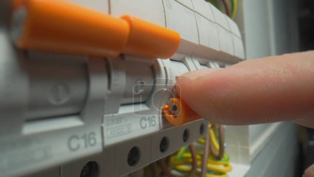 Photo for Finger turning on high voltage electrical switches in switchboard. Automatic fuses switch box. Close up, electric switch power supply turn on. Switch on circuit breakers. Automatic breakers switching - Royalty Free Image