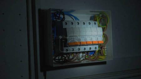 Téléchargez les photos : White electrical panel with many wires, electrical parts, automatic switches, breakers, residual current devices, fuses, terminals. High voltage automatic breaker switch, close up in the dark - en image libre de droit