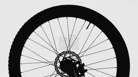 Photo for Black silhouette of a bicycle wheel on a white isolated background. Close up of round bike wheel with rubber tread tire, nipple, spokes and brake. Part of a rubber wheel from a sporty modern bicycle - Royalty Free Image