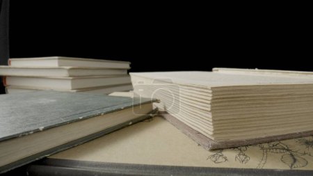 Photo for Open book with white paper pages isolated on black studio background. Old books with shabby covers lying on table in the library. Vintage textbooks. Ancient literature, publications. Close up - Royalty Free Image