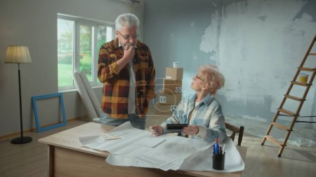 Photo for Elderly man and woman calculating expenses of repairing an apartment on calculator. Aged couple sitting at a table and planning the improvement of their home. Concept of repair, decoration, interior - Royalty Free Image