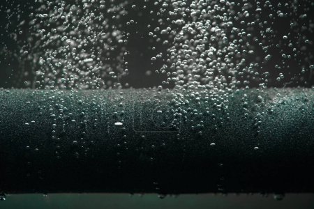 Téléchargez les photos : Petites bulles d'air brillantes s'échappant du tube de compresseur de paralon gris ou du filtre sous l'eau. Macro shot de l'équipement de travail pour l'aération de l'eau avec de l'oxygène dans l'aquarium. Bulles d'oxygène provenant de - en image libre de droit