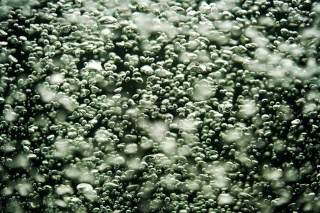 Photo for A stream of shiny air bubbles illuminated by light and shining on a dark background. Close up of light lit oxygen bubbles flow upwards. Aeration or filtration of liquid. Fizzy flow of air bubbles - Royalty Free Image
